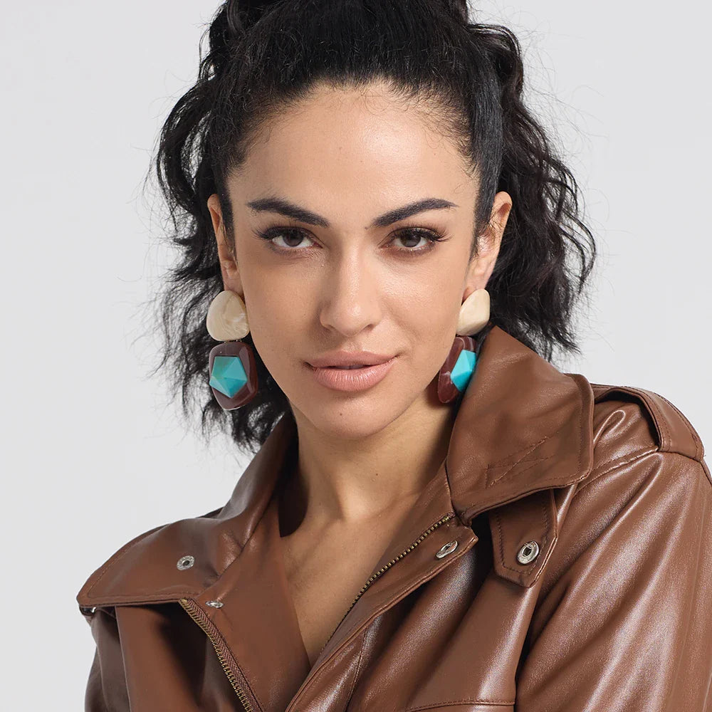 Woman standing proud and confident wearing bold earrings.